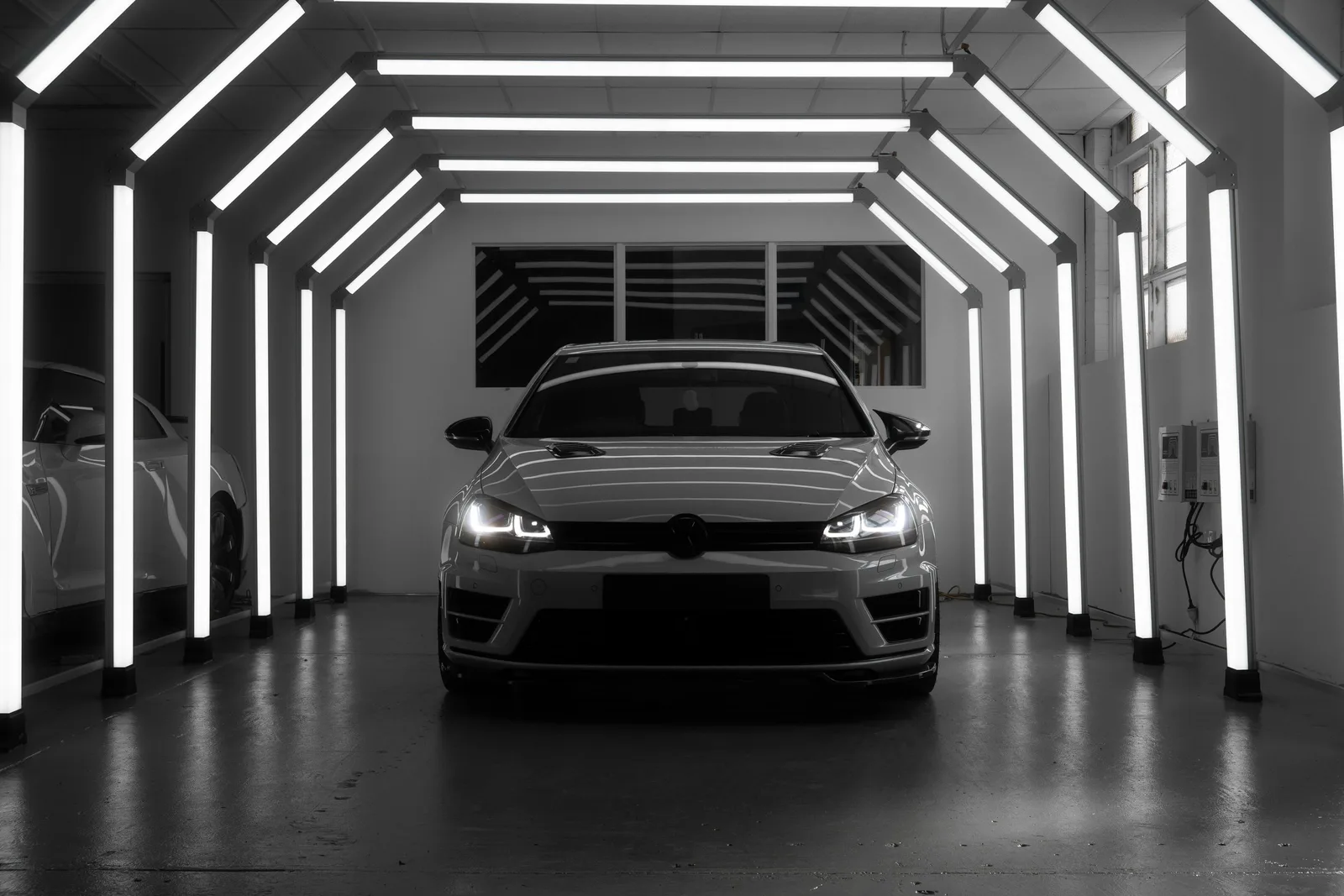 A Volkswagen Golf beneath the geometric workshop lights at Sunshine Accident Repair Centre